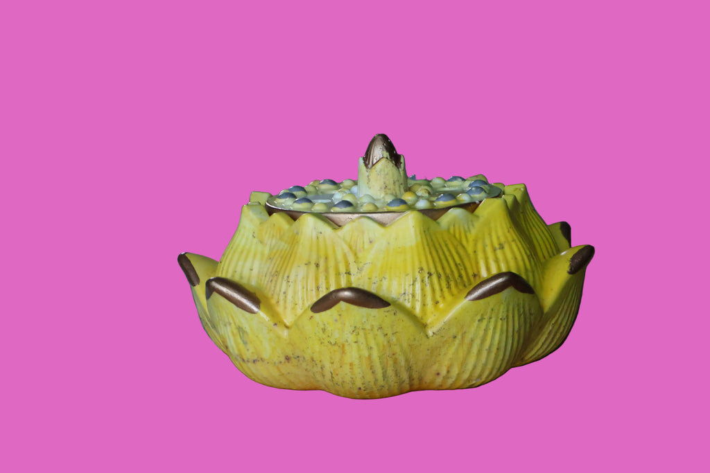 Yellow ceramic lotus flower on a wooden surface with a blurred background