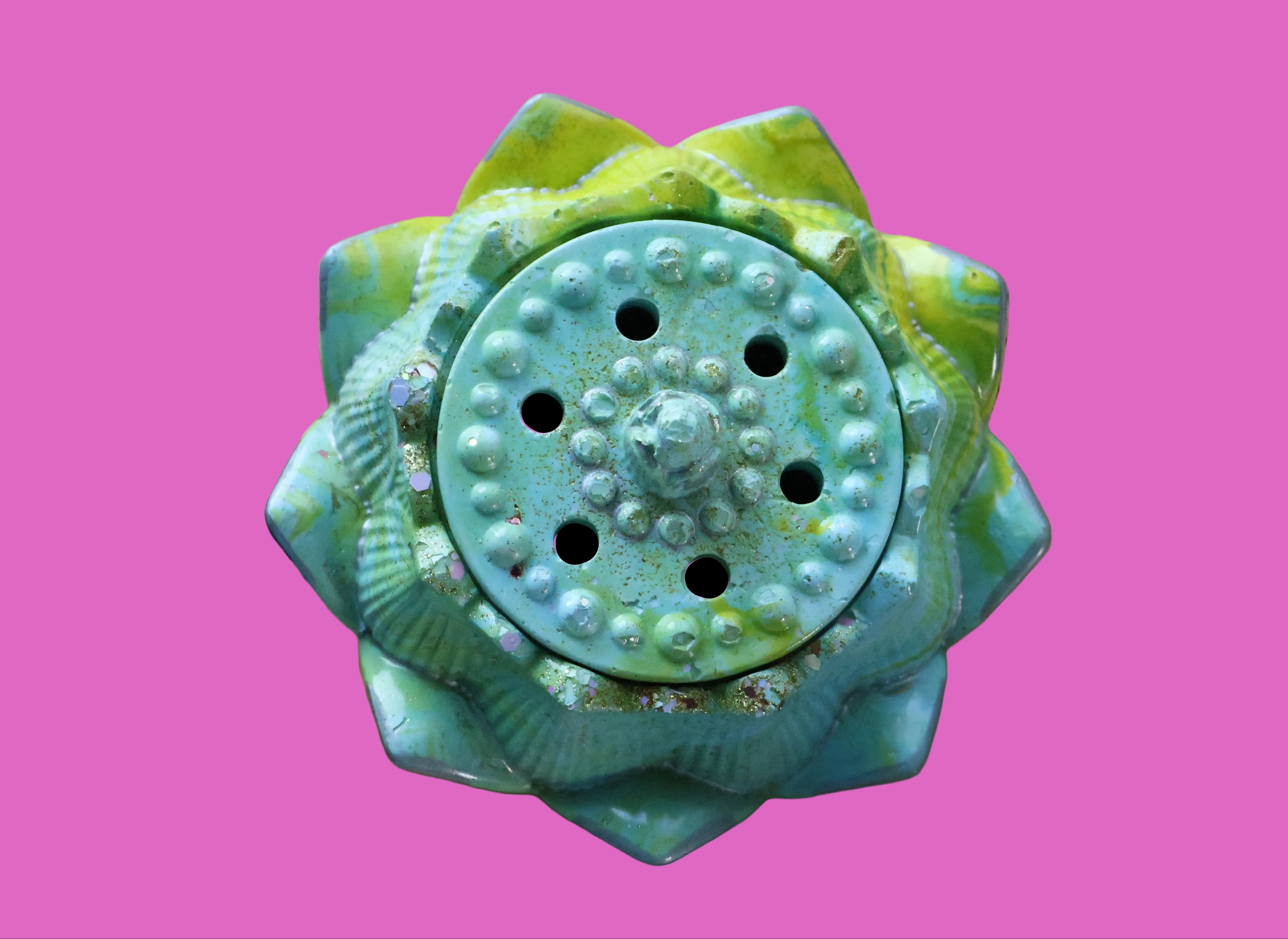 Decorative turquoise and green cement item on a wooden surface with a floral fabric background.