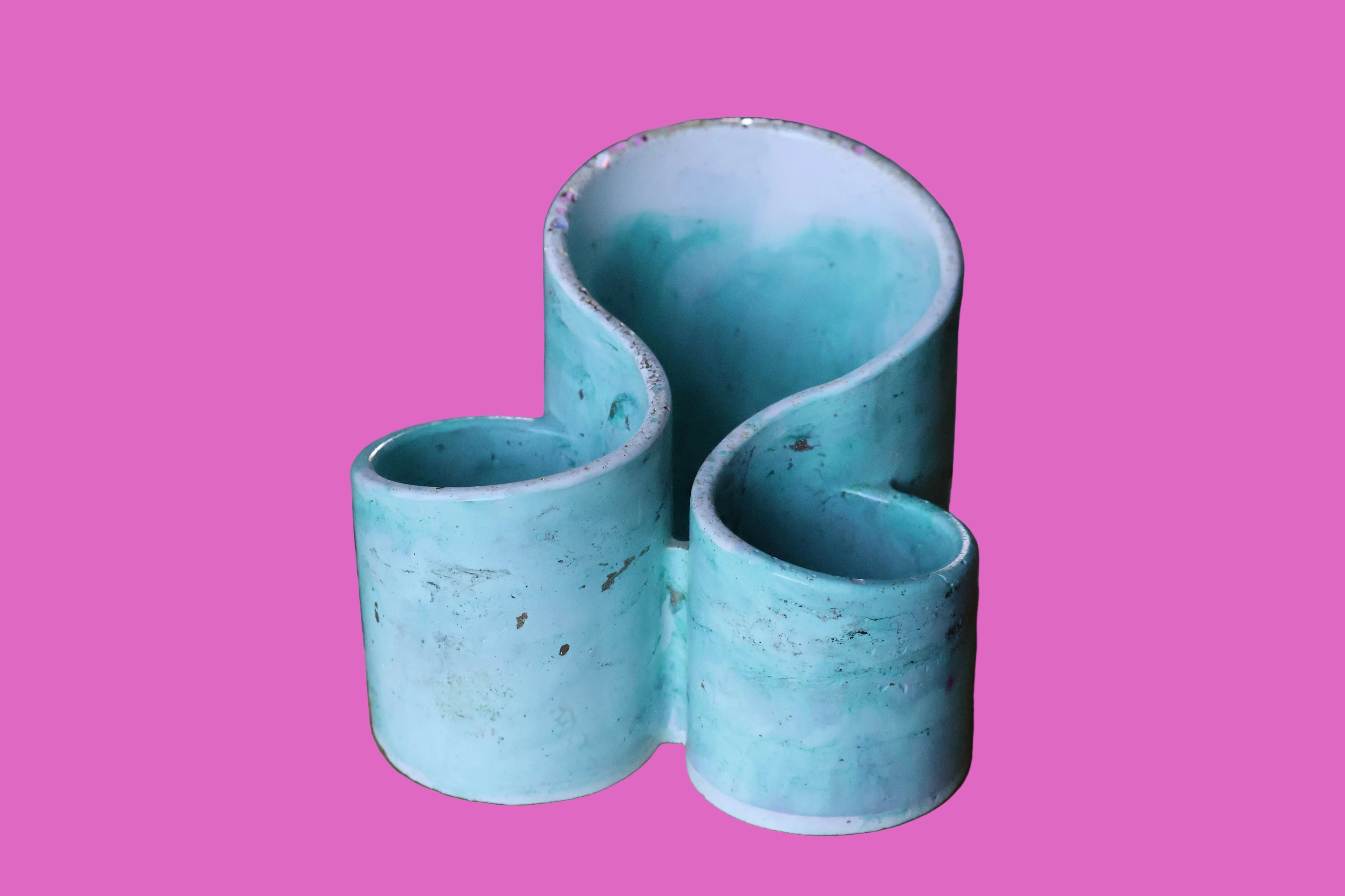 Turquoise cement vase with wavy design on a wooden surface